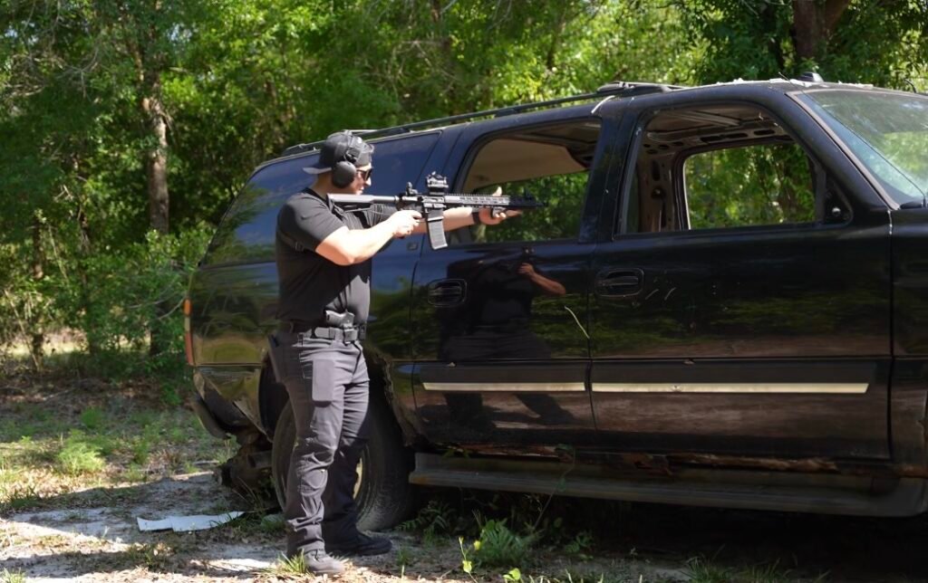 Student running a defensive pistol drill beside a vehicle
